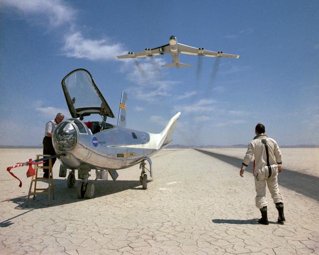 NASA image: NASA research pilot Bill Dana takes a moment to watch NASA's NB-52B cruise overhead after a research flight in the HL-10. On the left, John Reeves can be seen at the cockpit of the lifting body