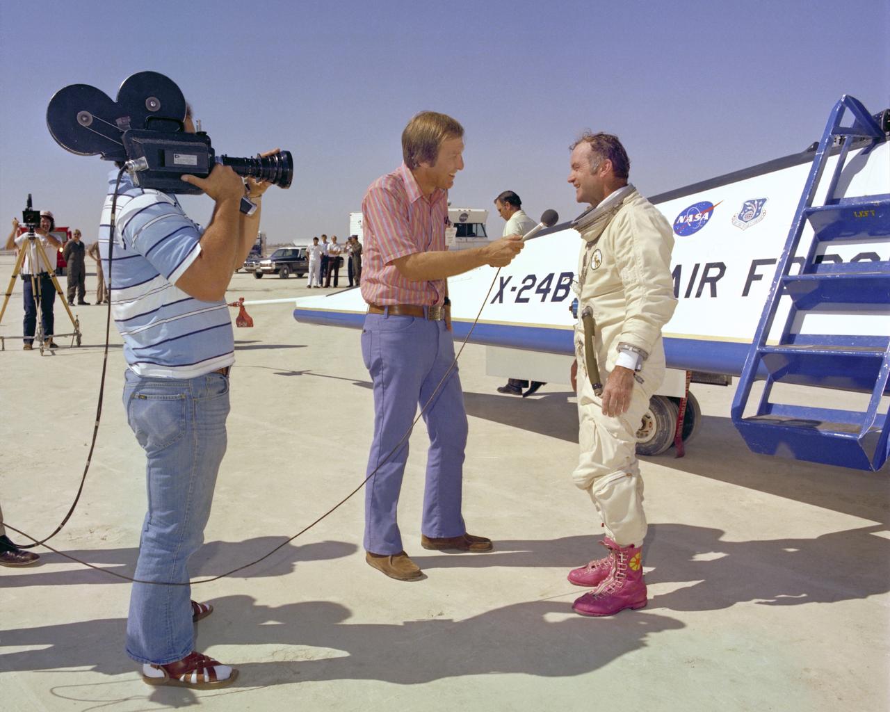 A TV reporter interviews NASA test pilot Bill Dana, wearing his infamous pink boots with yellow daisy decals, after the last powered flight of the X-24B.