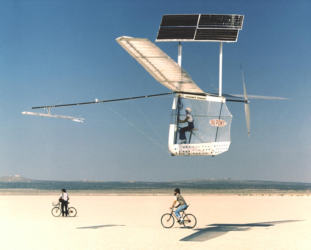Solar-powered Gossamer Penguin in flight with Janice Brown and Ray Morgan riding chase bicycle. 