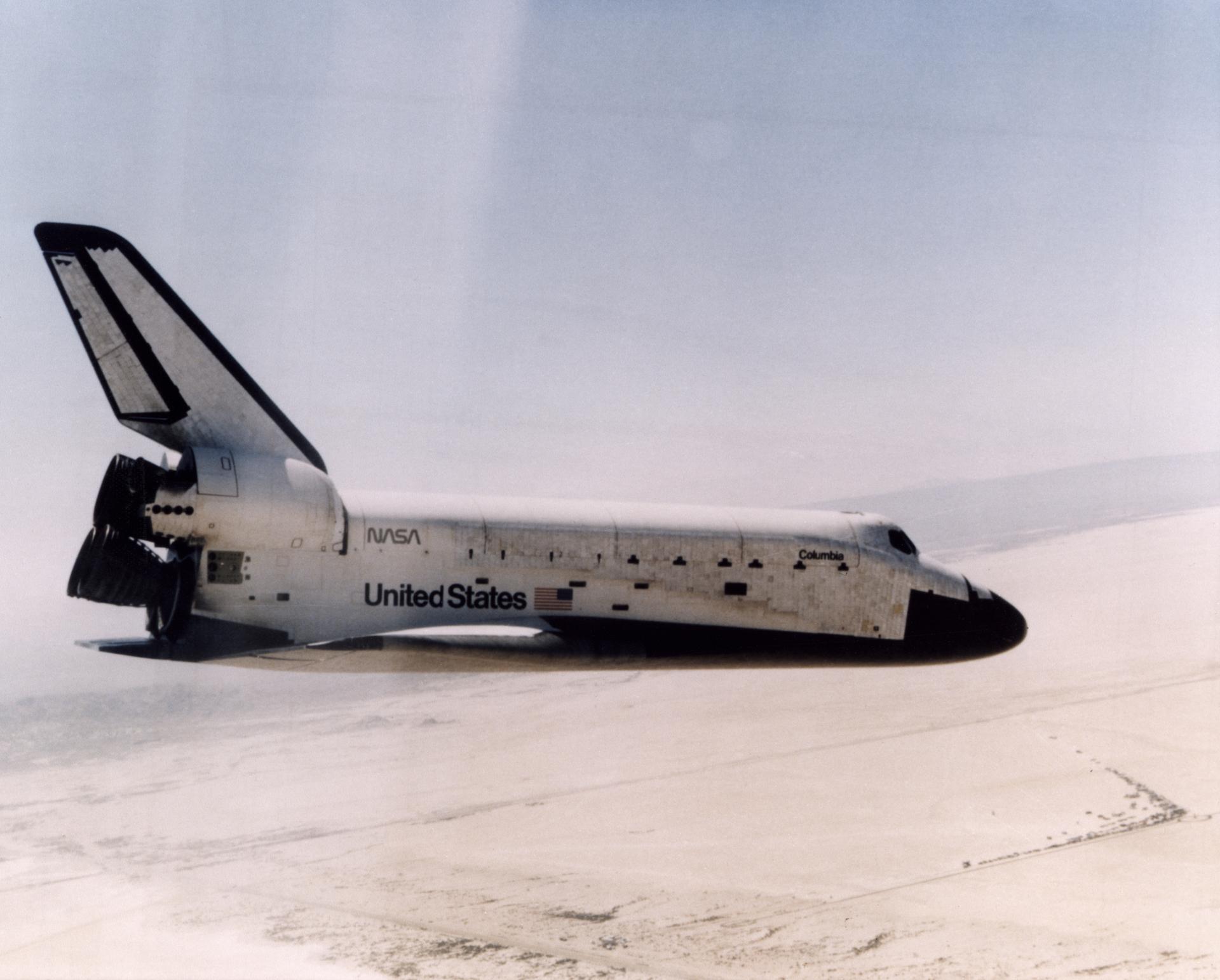 The Space Shuttle Columbia glides down over Rogers Dry Lake as it heads for a landing at Edwards Air Force Base at the conclusion of its first orbital mission on April 14, 1981.