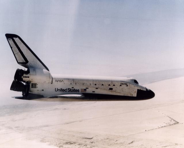NASA image: The Space Shuttle Columbia glides down over Rogers Dry Lake as it heads for a landing at Edwards Air Force Base at the conclusion of its first orbital mission