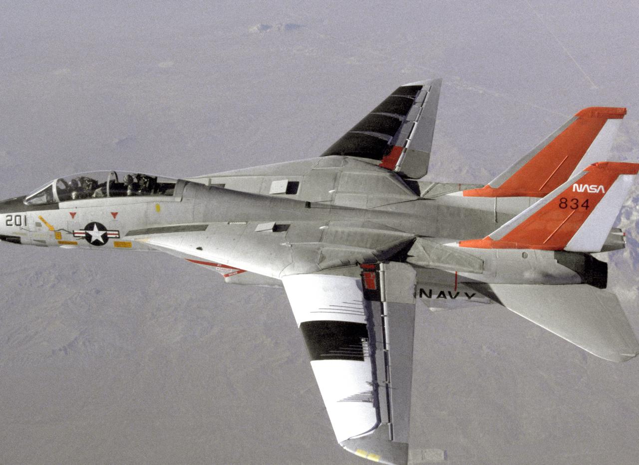 NASA 834, an F-14 Navy Tomcat, seen here in flight, was used at Dryden in 1986 and 1987 in a program known as the Variable-Sweep Transition Flight Experiment (VSTFE). This program explored laminar flow on variable sweep aircraft at high subsonic speeds.  An F-14 aircraft was chosen as the carrier vehicle for the VSTFE program primarily because of its variable-sweep capability, Mach and Reynolds number capability, availability, and favorable wing pressure distribution.  The variable sweep outer-panels of the F-14 aircraft were modified with natural laminar flow gloves to provide not only smooth surfaces but also airfoils that can produce a wide range of pressure distributions for which transition location can be determined at various flight conditions and sweep angles.  Glove I, seen here installed on the upper surface of the left wing, was a "cleanup" or smoothing of the basic F-14 wing, while Glove II was designed to provide specific pressure distributions at Mach 0.7.  Laminar flow research continued at Dryden with a research program on the NASA 848 F-16XL, a laminar flow experiment involving a wing-mounted panel with millions of tiny laser cut holes drawing off turbulent boundary layer air with a suction pump.