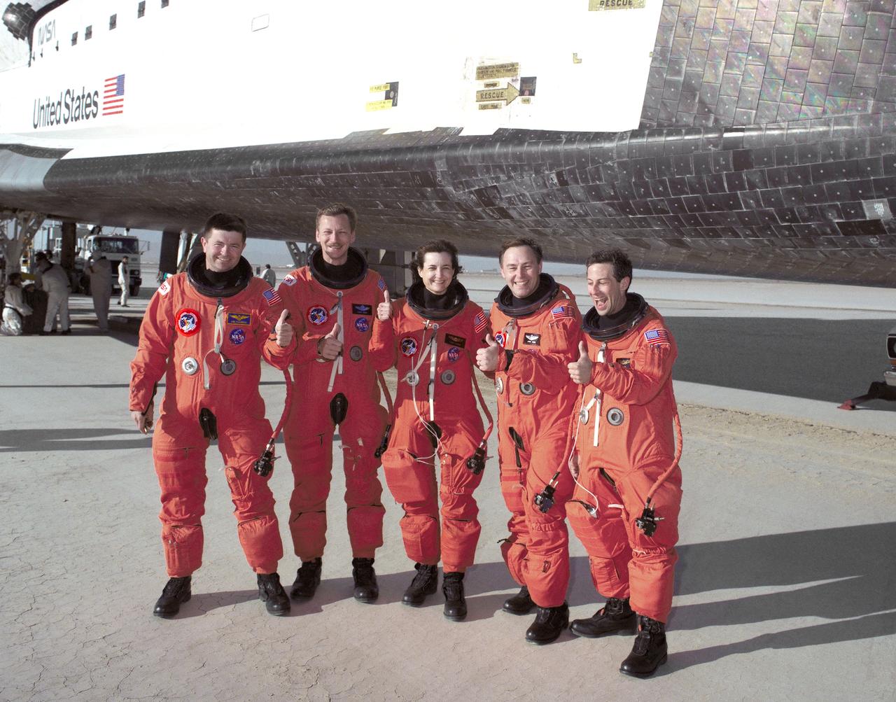 The crew of the Space Shuttle Atlantis gives the "all's well" thumb's-up sign after leaving the 100-ton orbiter following their landing at 6:55 a.m. (PDT), 11 April 1991, at NASA's Ames Dryden Flight Research Facility (later redesignated Dryden Flight Research Center), Edwards, California, to conclude mission STS-37. They are, from left, Kenneth D. Cameron, pilot; Steven R. Nagel, mission commander; and mission specialists Linda M. Godwin, Jerry L. Ross, and Jay Apt. During the mission,which began with launch April 5 at Kennedy Space Center, Florida, the crew deployed the Gamma Ray Observatory. Ross and Jay also carried out two spacewalks, one to deploy an antenna on the Gamma Ray Observatory and the other to test equipment and mobility techniques for the construction of the future Space Station. The planned five-day mission was extended one day because of high winds at Edwards.