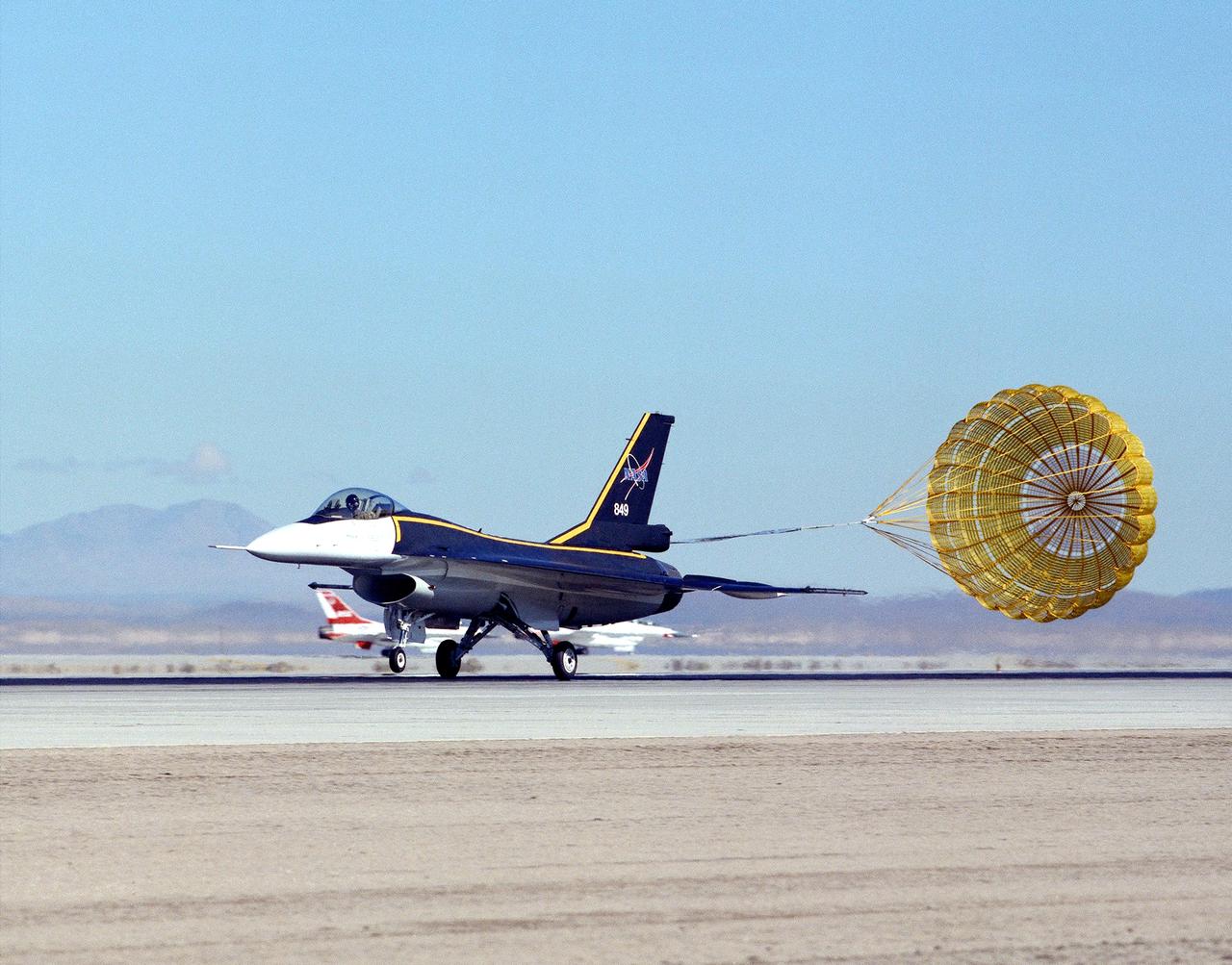 NASA's single-seat F-16XL makes a drag chute landing at the Dryden Flight Research Center, Edwards, California. The aircraft was most recently used in the Cranked-Arrow Wing Aerodynamics Project (CAWAP) to test boundary layer pressures and distribution.  Previously it had been used in a program to investigate the characteristics of sonic booms for NASA's High Speed Research Program. Data from the program will be used in the development of a high speed civilian transport. During the series of sonic boom research flights, the F-16XL was used to probe the shock waves being generated by a NASA SR-71 and record their shape and intensity.