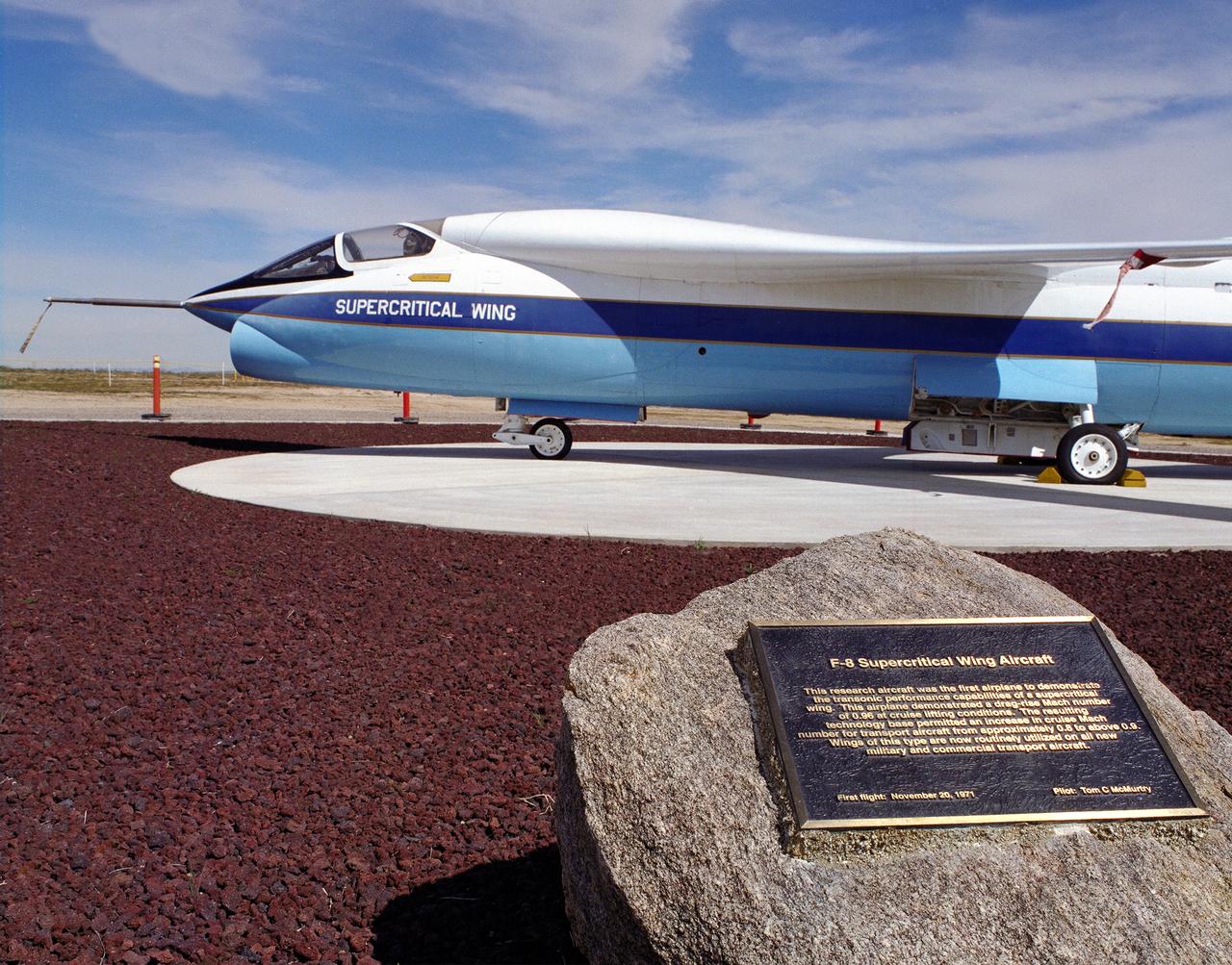A Vought F-8A Crusader was selected by NASA as the testbed aircraft (designated TF-8A) to install an experimental Supercritical Wing (SCW) in place of the conventional wing. The unique design of the Supercritical Wing reduces the effect of shock waves on the upper surface near Mach 1, which in turn reduces drag.  In the photograph the TF-8A Crusader with the Supercritical Wing is shown on static display in front of the NASA Dryden Flight Research Center, Edwards, California. The F-8 SCW aircraft, along with the F-8 Digital Fly-By-Wire aircraft were placed on display on May 27, 1992, at a conference marking the 20th anniversary of the start of the two programs.