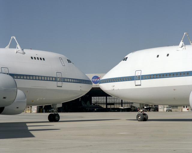 NASA image: The NASA logo on a hangar is framed by the noses of NASA's two modified 747 Shuttle Carrier Aircraft on the ramp at NASA Dryden in this 1995 photo