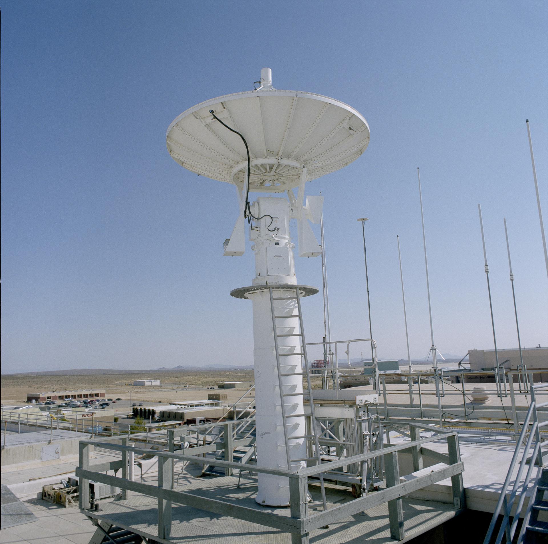 A pedestal and dish are positioned on a rooftop.