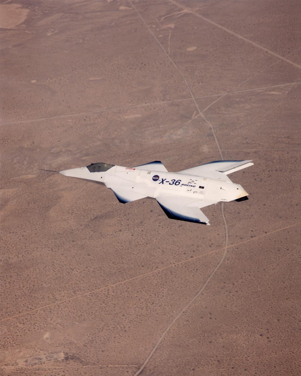 The tailless X-36 technology demonstrator research aircraft cruises over the California desert at low altitude during a 1997 research flight.