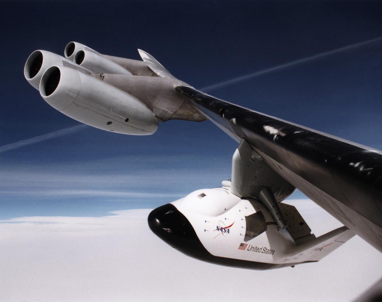 A unique, close-up view of the X-38 under the wing of NASA's B-52 mothership prior to launch of the lifting-body research vehicle. The photo was taken from the observation window of the B-52 bomber as it banked in flight.