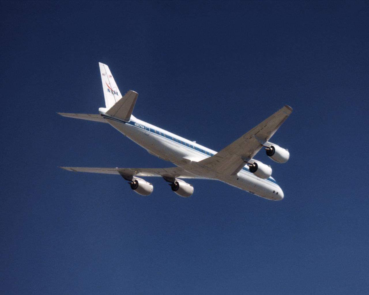 The NASA DC-8 in a right bank over the rugged Sierra Nevada Mountains. The former airliner is a "dash-72" model and has a range of 5,500 miles. The craft can stay airborne for 12 hours and has an operational speed range between 300 and 500 knots. The research flights are made at between 500 and 41,000 feet. The aircraft can carry up to 30,000 lbs of research/science payload equipment installed in 15 mission-definable spaces. In this photo, the aircraft is shown in flight from below, with the DC-8 silhouetted against a blue sky.