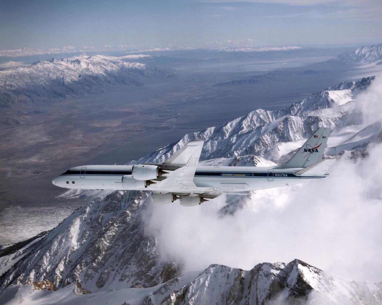 DC-8 Airborne Laboratory in banked flight over snow-capped Sierra Nevada mountain range