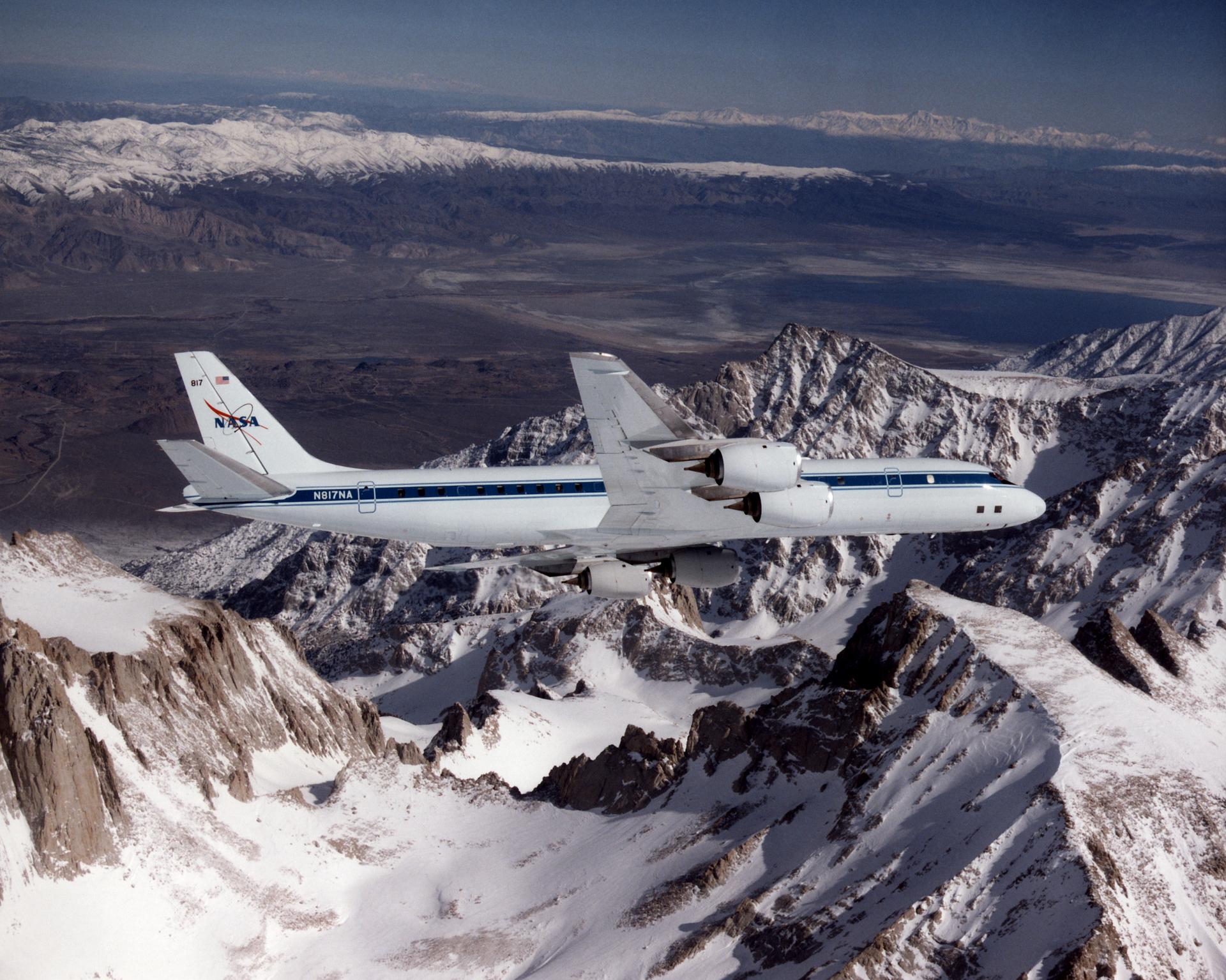 DC-8 in flight over snow capped mountains.