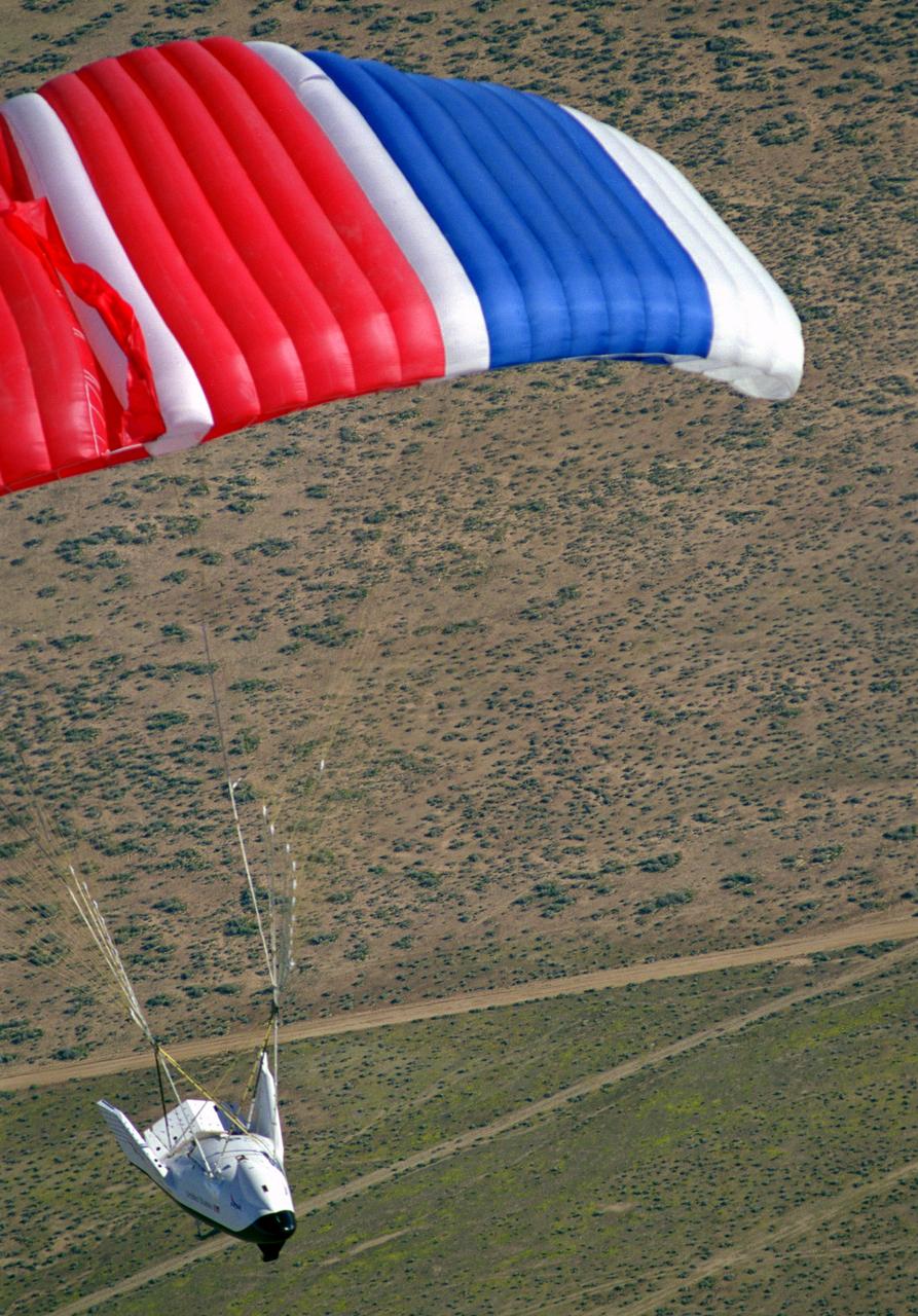 The X-38 Crew Return Vehicle descends under its steerable parafoil over the California desert in its first free flight at the Dryden Flight Research Center, Edwards, California. The flight took place March 12, 1998.