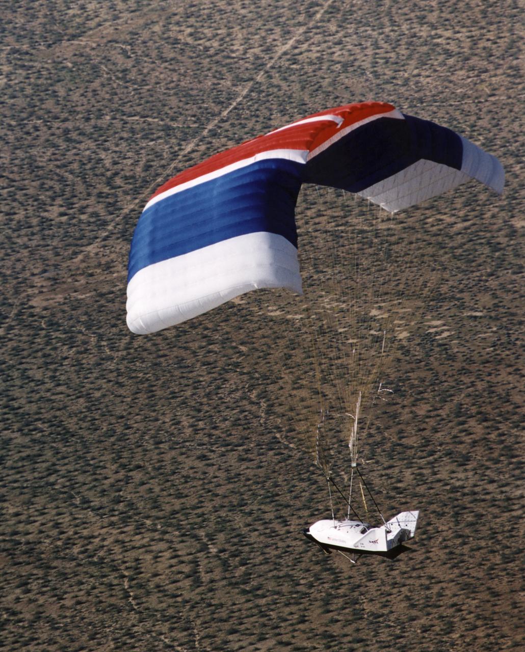 The X-38 Crew Return Vehicle descends under its steerable parafoil over the California desert in its first free flight at the Dryden Flight Research Center, Edwards, California. The flight took place March 12, 1998.