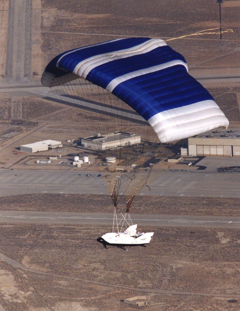 NASA's X-38, a research vehicle developed as part of an effort to build an emergency Crew Return Vehicle (CRV) for the International Space Station, descends toward the desert floor under its steerable parafoil on its second free flight. The X-38 was launched from NASA Dryden's B-52 Mothership on Saturday, February 6, 1999, from an altitude of approximately 23,000 feet.