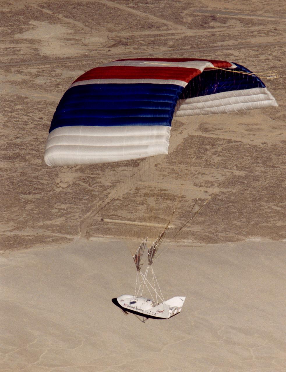 The X-38, a research vehicle built to help develop technology for an emergency Crew Return Vehicle (CRV), descends under its steerable parafoil on a March 1999 test flight at the Dryden Flight Research Center, Edwards, California.