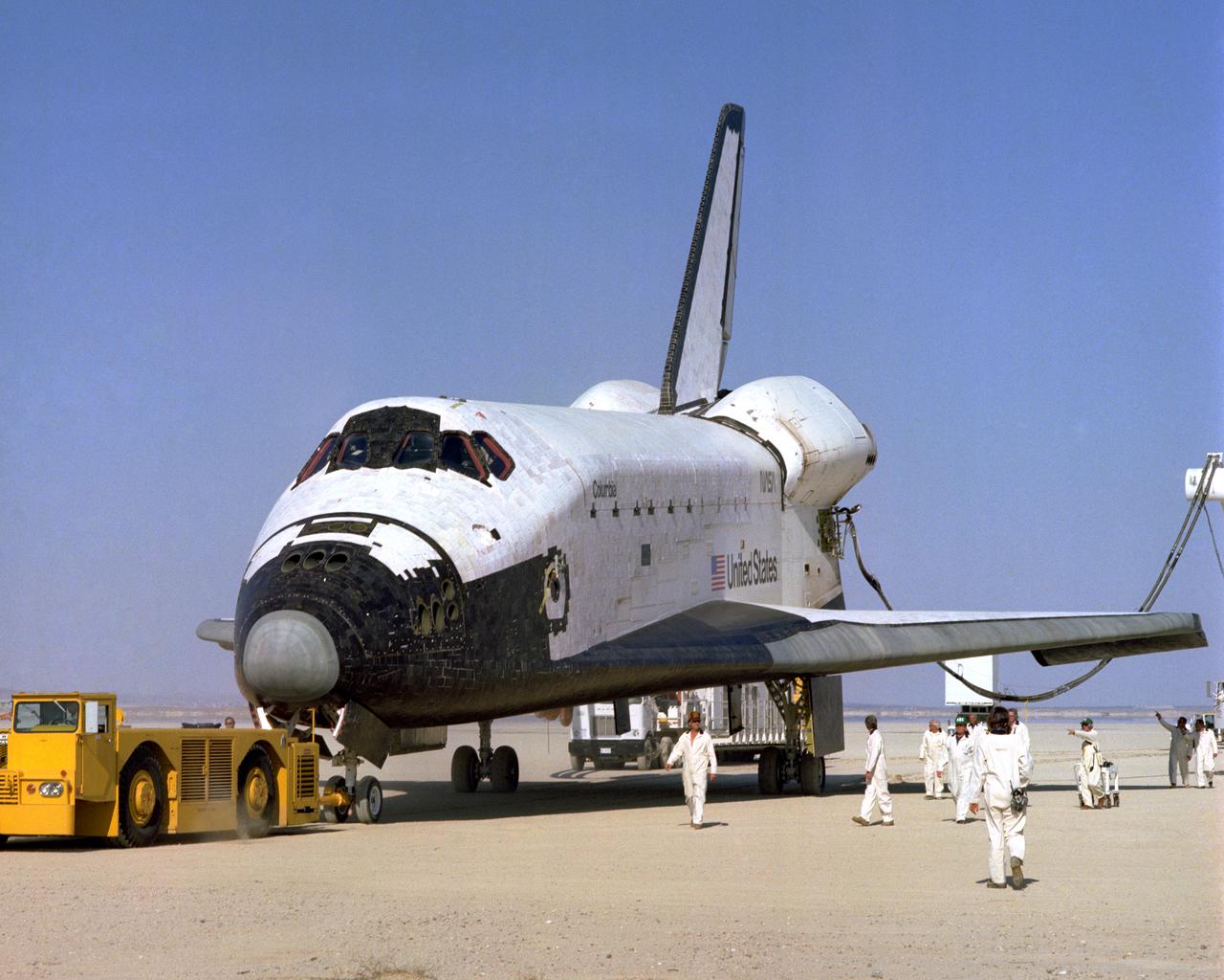 The Space Shuttle Columbia on Rogers Dry lakebed at Edwards AFB after landing to complete its first orbital mission on April 14, 1981. Technicians towed the Shuttle back to the NASA Dryden Flight Research Center for post-flight processing and preparation for a return ferry flight atop a modified 747 to Kennedy Space Center in Florida.
