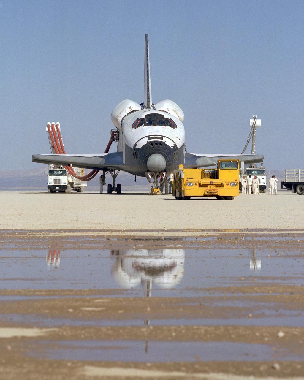 The Space Shuttle Columbia on Rogers Dry lakebed at Edwards AFB after landing to complete its first orbital mission on April 14, 1981. Technicians towed the Shuttle back to the NASA Dryden Flight Research Center for post-flight processing and preparation for a return ferry flight atop a modified 747 to Kennedy Space Center in Florida.