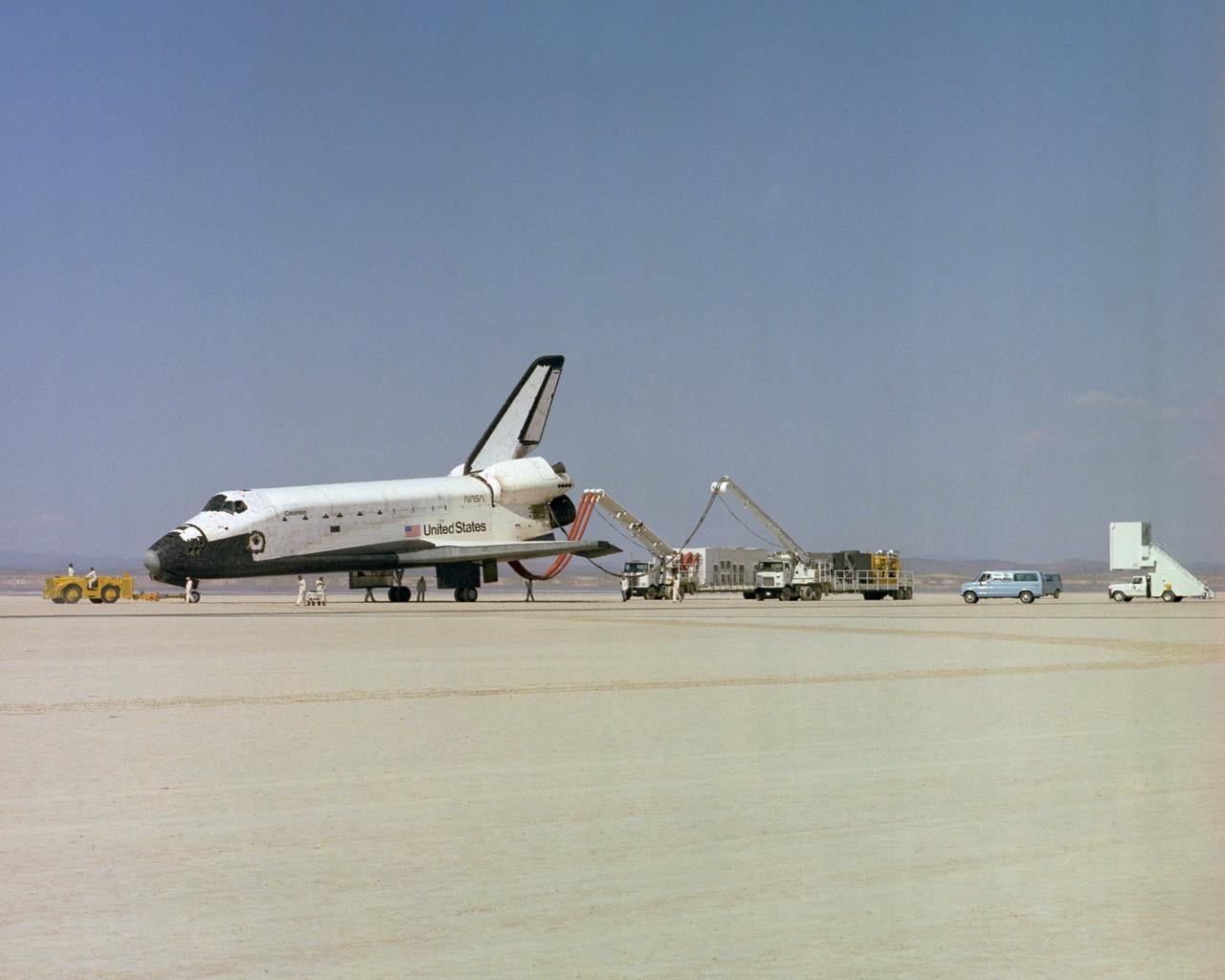 The Space Shuttle Columbia on Rogers Dry lakebed at Edwards AFB after landing to complete its first orbital mission on April 14, 1981. Technicians towed the Shuttle back to the NASA Dryden Flight Research Center for post-flight processing and preparation for a return ferry flight atop a modified 747 to Kennedy Space Center in Florida.