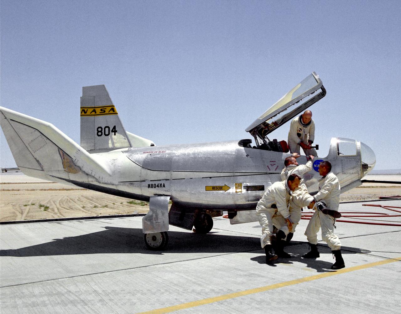 Not every moment of a test pilot's day is serious business. In a moment of levity, NASA pilots Bill Dana (left) and John A. Manke try to drag Air Force test pilot Peter Hoag away from the HL-10 lifting body while Air Force Major Jerauld R. Gentry helps from the cockpit. These four men were the principal pilots for the HL-10 program. This was not the only prank involving the HL-10 and its pilots. Once "Captain Midnight" (Gentry) and the "Midnight Skulkers" sneaked into the NASA hangar and put "U.S. Air Force" on the aircraft using stick-on letters. Later, while Gentry was making a lifting-body flight, his 1954 Ford was "borrowed" from the parking lot, painted with yellow-green zinc-chromate primer, and decorated with large stick-on flowers about one foot in diameter. After Gentry returned from the flight, he was surprised to see what had happened to his car.