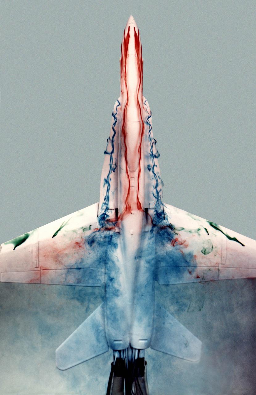 This image shows a plastic 1/48-scale model of an F-18 aircraft inside the "Water Tunnel" more formally known as the NASA Dryden Flow Visualization Facility. Water is pumped through the tunnel in the direction of normal airflow over the aircraft; then, colored dyes are pumped through tubes with needle valves. The dyes flow back along the airframe and over the airfoils highlighting their aerodynamic characteristics. The aircraft can also be moved through its pitch axis to observe airflow disruptions while simulating actual flight at high angles of attack. The Water Tunnel at NASA's Dryden Flight Research Center, Edwards, CA, became operational in 1983 when Dryden was a Flight Research Facility under the management of the Ames Research Center in Mountain View, CA. As a medium for visualizing fluid flow, water has played a significant role. Its use dates back to Leonardo da Vinci (1452-1519), the Renaissance Italian engineer, architect, painter, and sculptor. In more recent times, water tunnels have assisted the study of complex flows and flow-field interactions on aircraft shapes that generate strong vortex flows. Flow visualization in water tunnels assists in determining the strength of vortices, their location, and possible methods of controlling them.  The design of the Dryden Water Tunnel imitated that of the Northrop Corporation's tunnel in Hawthorne, CA. Called the Flow Visualization Facility, the Dryden tunnel was built to assist researchers in understanding the aerodynamics of aircraft configured in such a way that they create strong vortex flows, particularly at high angles of attack. The tunnel provides results that compare well with data from aircraft in actual flight in another fluid-air. Other uses of the tunnel have included study of how such flight hardware as antennas, probes, pylons, parachutes, and experimental fixtures affect airflow. The facility has also been helpful in finding the best locations for emitting smoke from flight vehicles for flow vi
