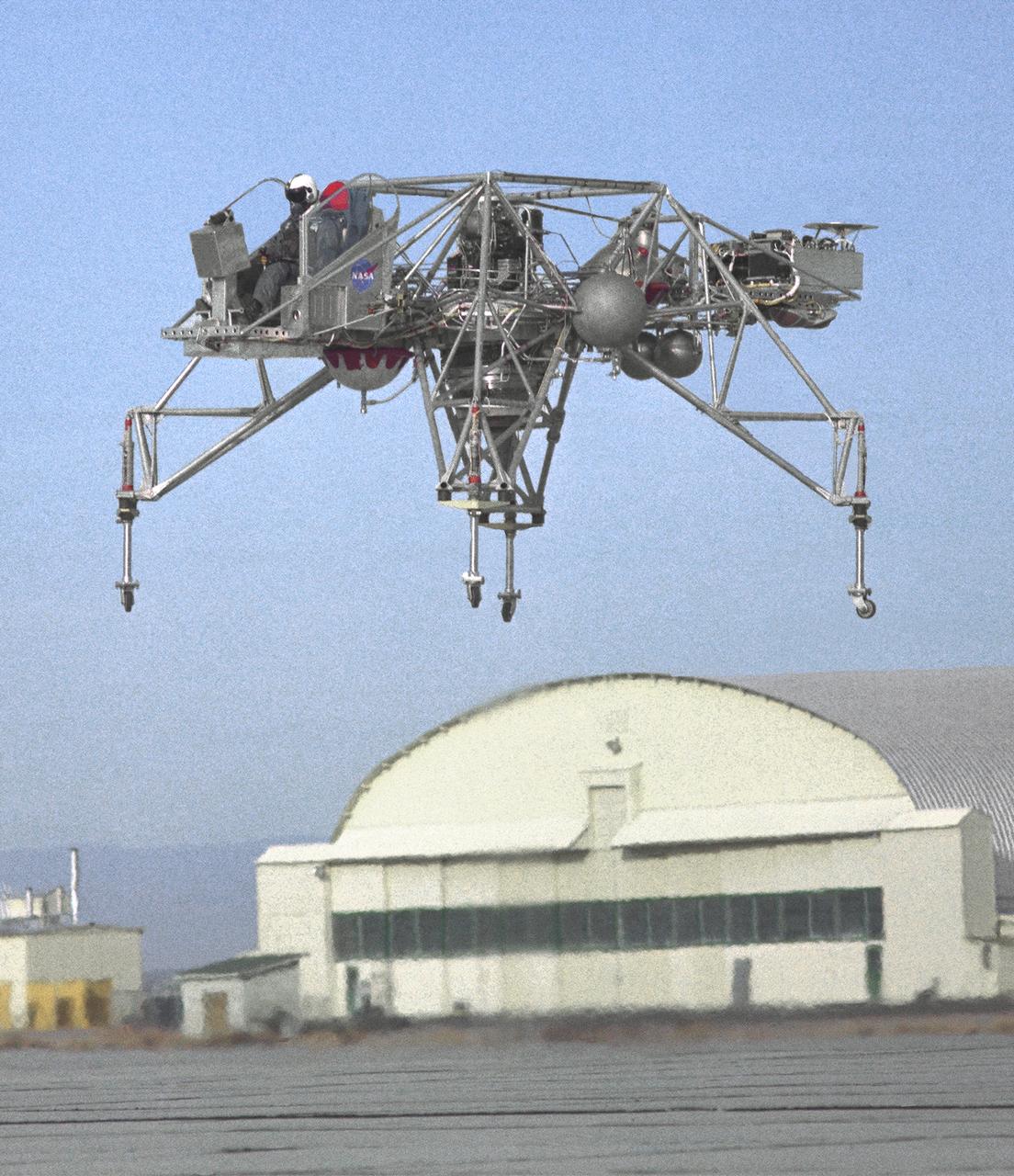 An inflight view from the left side of the Lunar Landing Research Vehicle, is shown in this 1964 NASA Flight Research Center photograph. The photograph was taken in front of the old NACA hangar located at the South Base, Edwards Air Force Base. When Apollo planning was underway in 1960, NASA was looking for a simulator to profile the descent to the Moon's surface. Three concepts surfaced: an electronic simulator, a tethered device, and the ambitious Dryden contribution, a free-flying vehicle. All three became serious projects, but eventually the NASA Flight Research Center's (FRC) Landing Research Vehicle (LLRV) became the most significant one. Hubert M. Drake is credited with originating the idea, while Donald Bellman and Gene Matranga were senior engineers on the project, with Bellman, the project manager. Simultaneously, and independently, Bell Aerosystems Company, Buffalo, N.Y., a company with experience in vertical takeoff and landing (VTOL) aircraft, had conceived a similar free-flying simulator and proposed their concept to NASA headquarters. NASA Headquarters put FRC and Bell together to collaborate. The challenge was; to allow a pilot to make a vertical landing on earth in a simulated Moon environment, one sixth of the earth's gravity and with totally transparent aerodynamic forces in a "free flight" vehicle with no tether forces acting on it.  Built of tubular aluminum like a giant four-legged bedstead, the vehicle was to simulate a lunar landing profile from around 1500 feet to the Moon's surface. To do this, the LLRV had a General Electric CF-700-2V turbofan engine mounted vertically in gimbals, with 4200 pounds of thrust. The engine, using JP-4 fuel, got the vehicle up to the test altitude and was then throttled back to support five-sixths of the vehicle's weight, simulating the reduced gravity of the Moon. Two hydrogen-peroxide lift rockets with thrust that could be varied from 100 to 500 pounds handled the LLRV's rate of descent and horizontal transla