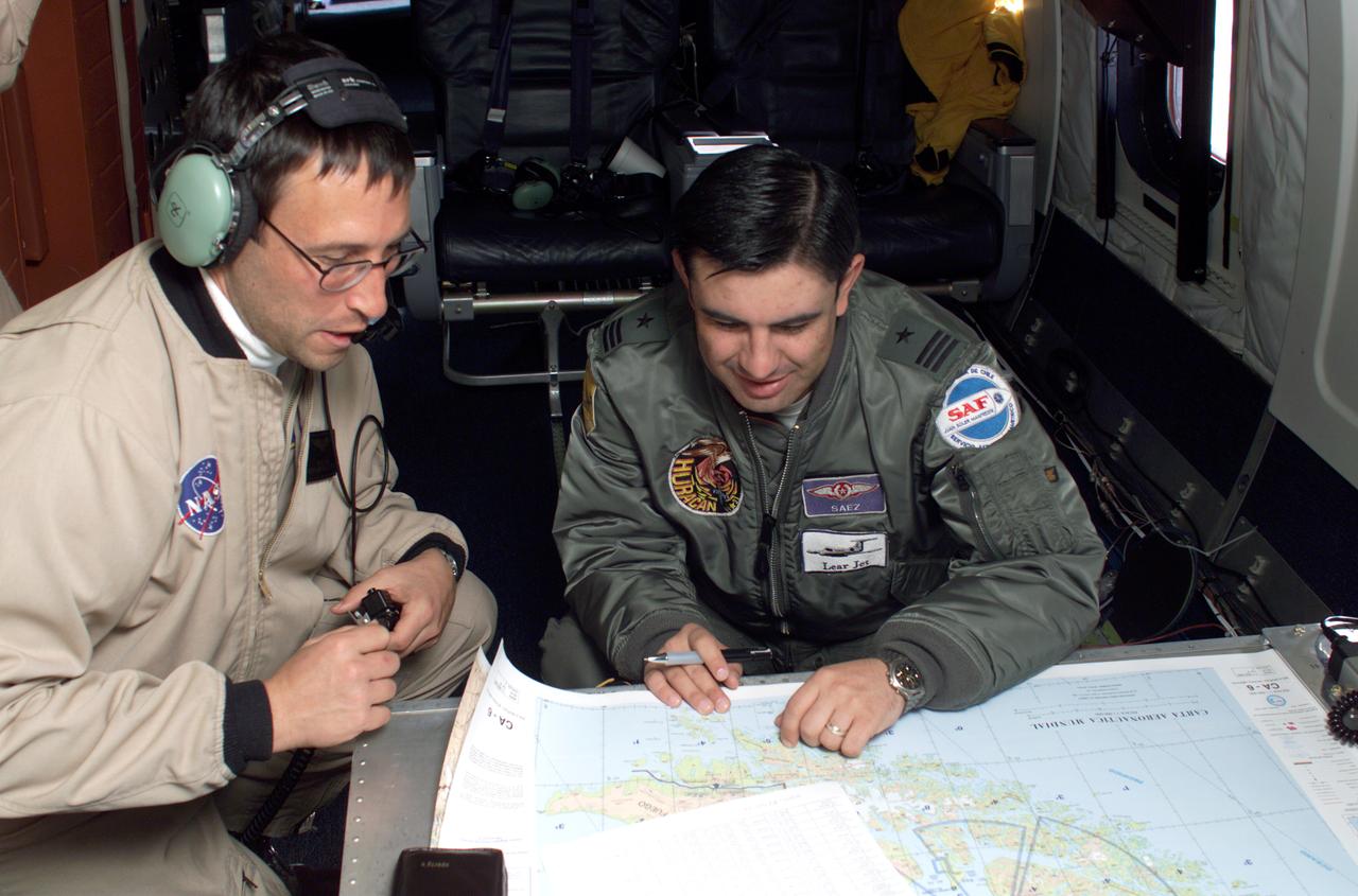 NASA DC-8 Mission Manager Walter Klein and Chilean Air Force Advisor Captain Saez review maps of the Antarctic Peninsula during an AirSAR 2004 mission. AirSAR 2004 is a three-week expedition in Central and South America by an international team of scientists that is using an all-weather imaging tool, called the Airborne Synthetic Aperture Radar (AirSAR), located onboard NASA's DC-8 airborne laboratory. Scientists from many parts of the world are combining ground research with NASA's AirSAR technology to improve and expand on the quality of research they are able to conduct. These photos are from the DC-8 aircraft while flying an AirSAR mission over Antarctica. The Antarctic Peninsula is more similar to Alaska and Patagonia than to the rest of the Antarctic continent. It is drained by fast glaciers, receives abundant precipitation, and melts significantly in the summer months. In recent decades, the Peninsula has experienced significant atmospheric warming (about 2 degrees C since 1950), which has triggered a vast and spectacular retreat of its floating ice shelves, glacier reduction, a decrease in permanent snow cover and a lengthening of the melt season. As a result, the contribution to sea level from this region could be rapid and substantial. With an area of 120,000 km, or ten times the Patagonia ice fields, the Peninsula could contribute as much as 0.4mm/yr sea level rise, which would be the largest single contribution to sea level from anywhere in the world.  This region is being studied by NASA using a DC-8 equipped with the Airborne Synthetic Aperture Radar developed by scientists from NASA’s Jet Propulsion Laboratory. AirSAR will provide a baseline model and unprecedented mapping of the region. This data will make it possible to determine whether the warming trend is slowing, continuing or accelerating. AirSAR will also provide reliable information on ice shelf thickness to measure the contribution of the glaciers to sea level.