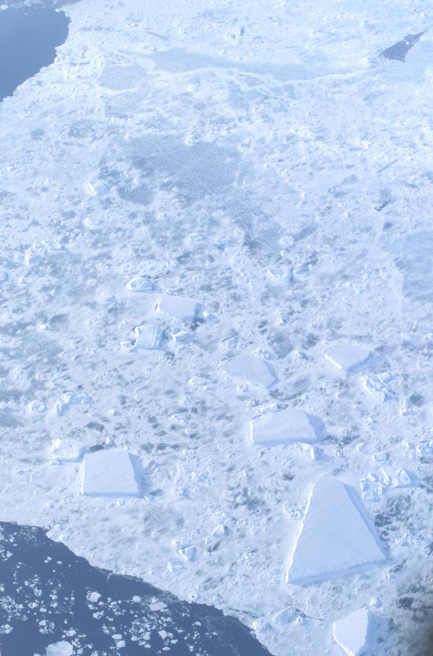 The Larsen Ice Shelf in Antarctica viewed from NASA's DC-8 aircraft during the AirSAR 2004 campaign. AirSAR 2004 is a three-week expedition in Central and South America by an international team of scientists that is using an all-weather imaging tool, called the Airborne Synthetic Aperture Radar (AirSAR), located onboard NASA's DC-8 airborne laboratory. Scientists from many parts of the world are combining ground research with NASA's AirSAR technology to improve and expand on the quality of research they are able to conduct. These photos are from the DC-8 aircraft while flying an AirSAR mission over Antarctica. The Antarctic Peninsula is more similar to Alaska and Patagonia than to the rest of the Antarctic continent. It is drained by fast glaciers, receives abundant precipitation, and melts significantly in the summer months. In recent decades, the Peninsula has experienced significant atmospheric warming (about 2 degrees C since 1950), which has triggered a vast and spectacular retreat of its floating ice shelves, glacier reduction, a decrease in permanent snow cover and a lengthening of the melt season. As a result, the contribution to sea level from this region could be rapid and substantial. With an area of 120,000 km, or ten times the Patagonia ice fields, the Peninsula could contribute as much as 0.4mm/yr sea level rise, which would be the largest single contribution to sea level from anywhere in the world.  This region is being studied by NASA using a DC-8 equipped with the Airborne Synthetic Aperture Radar developed by scientists from NASA’s Jet Propulsion Laboratory. AirSAR will provide a baseline model and unprecedented mapping of the region. This data will make it possible to determine whether the warming trend is slowing, continuing or accelerating. AirSAR will also provide reliable information on ice shelf thickness to measure the contribution of the glaciers to sea level.