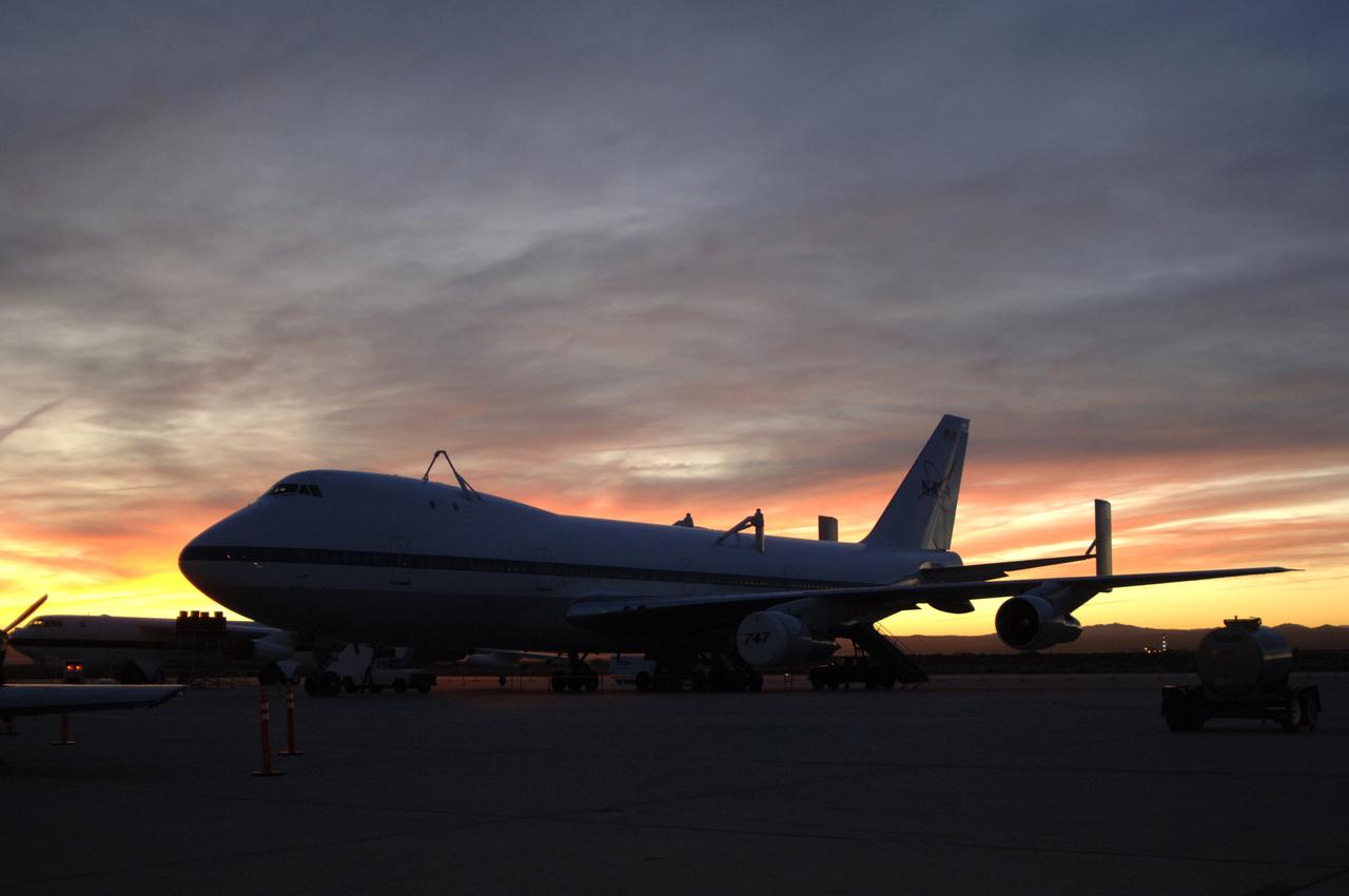 One of NASA's two modified Boeing 747 Shuttle Carrier Aircraft is silhouetted against the morning sky at sunrise on the ramp at Edwards Air Force Base.