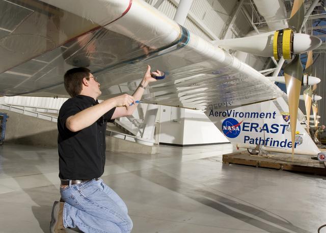 NASA image: AeroVironment crew chief Mark Shipley applies sealing tape to a wing joint on Pathfinder-Plus before it is hoisted into place at the NASM's Udvar-Hazy Center.