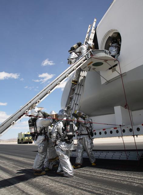 NASA image: Air Force fire/rescue crew enter the space shuttle cabin mockup hatch to evacuate the shuttle crew during a shuttle rescue training exercise at Edwards AFB