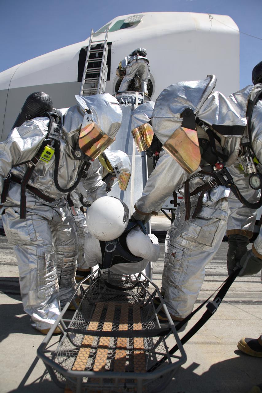 Air Force fire/rescue crew place a volunteer "injured astronaut" on a stretcher after exiting the shuttle cabin mockup during the training exercise. (USAF photo # 070505-F-1287F-126)
