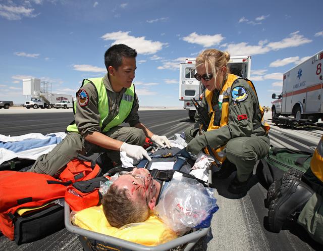 Complete with makeup to simulate facial injuries, a volunteer "astronaut" is tended to by aeromedical rescue staff after evacuation from the shuttle mockup