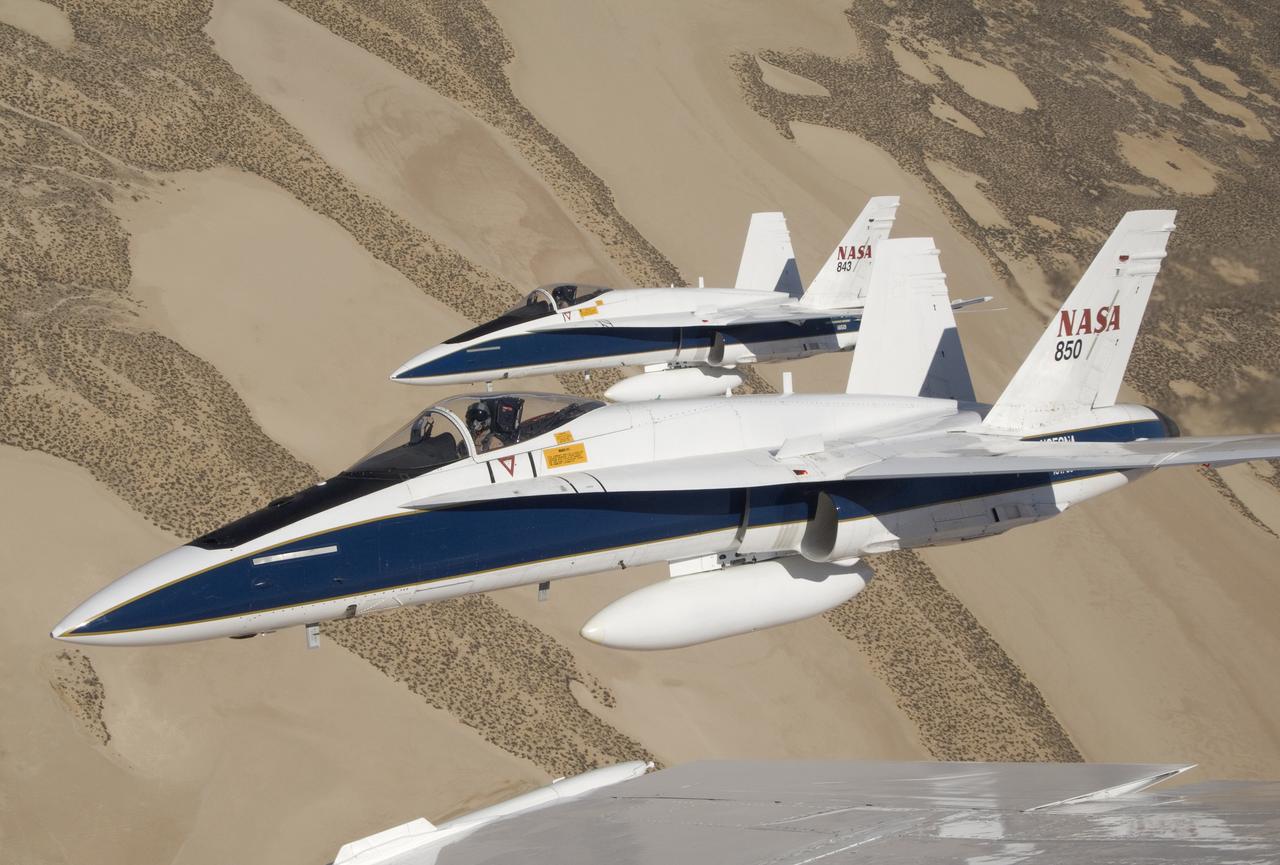 Two NASA Dryden F/A-18s flown by research pilots Frank Batteas and Nils Larson were captured by photographer Lori Losey from a third F/A-18 flown by Dick Ewers as they flew in tight formation over the desert at Edwards Air Force Base.