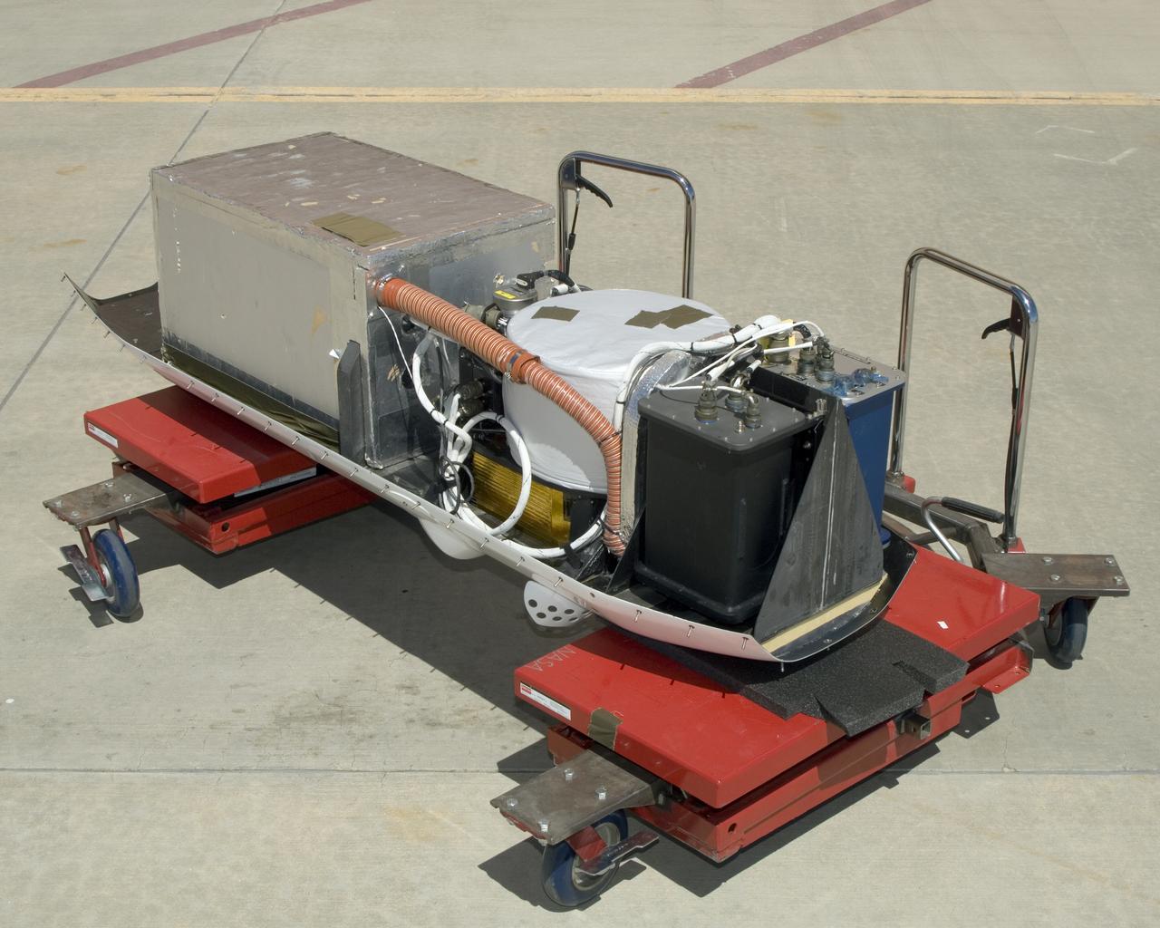 The instruments that make up the Ames Autonomous Module Scanner (AMS) that provided precise thermal-infrared imaging during the Western States Fire Mission in 2007 are detailed in this photo of the AMS as mounted on Ikhana's pod tray. The large foil-covered foam-insulated box at left covers the pressure vessel containing the data system computers and other electronics. The round white-topped assembly is the scan head, including the scan mirror, folded telescope, blackbody references, spectrometer and detectors. Two pressure boxes visible at the forward end of the tray contain the Applanix POS/AV precision navigation subsystem (black) and the power distributor including circuit breakers and ancillary wiring, scan motor controller and the blackbody reference temperature controller (blue).