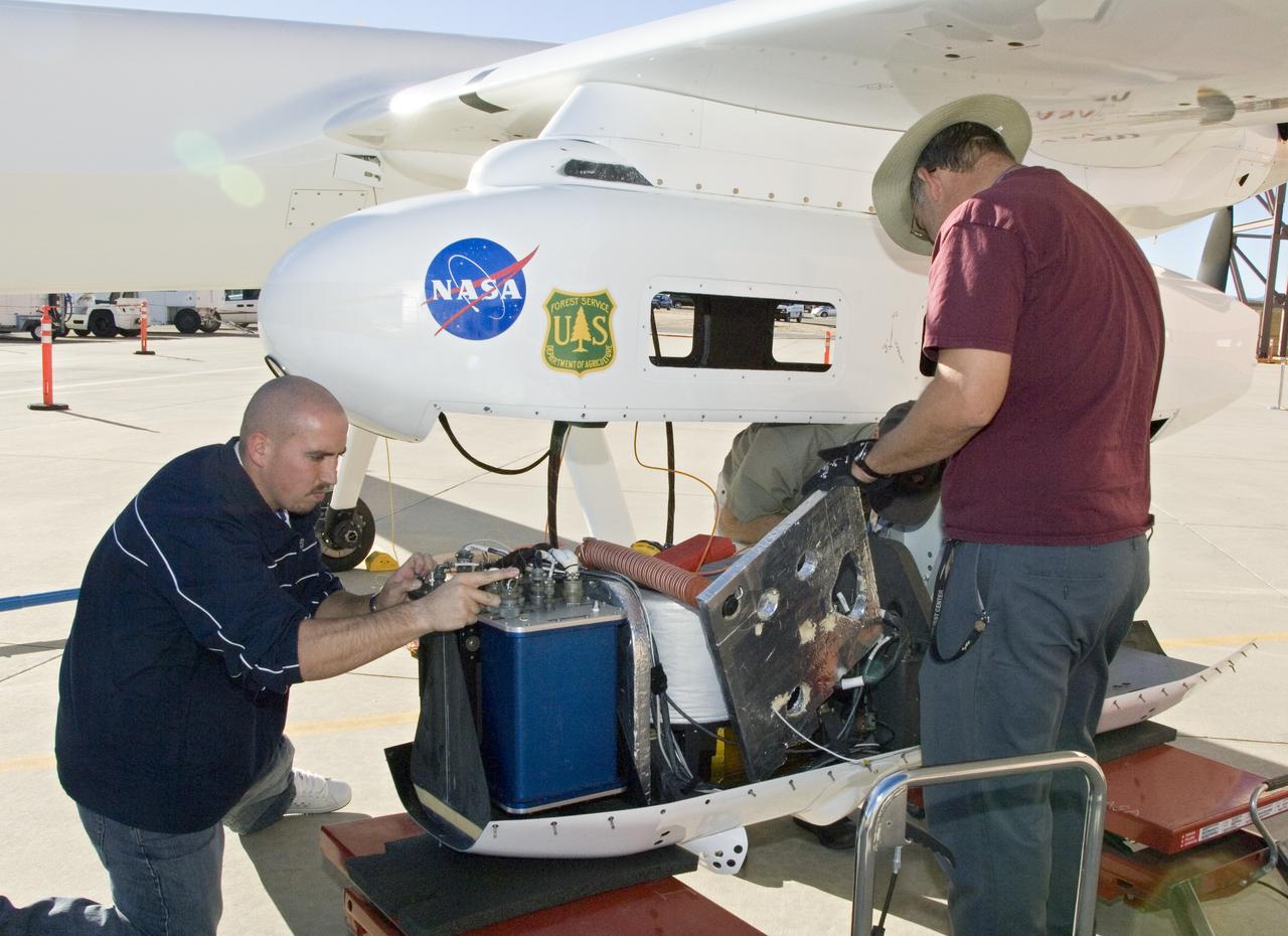 NASA Dryden's Ikhana ground crewmen Gus Carreno and James Smith load the thermal-infrared imaging scanner pallet into the Ikhana's underwing payload pod.