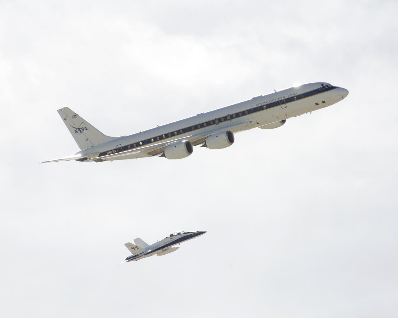 NASA's DC-8 airborne science laboratory is shadowed by a NASA F/A-18 chase plane during a flyover of the Dryden Aircraft Operations Facility in Palmdale, Calif.