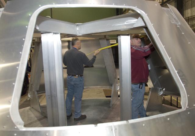 NASA Dryden technicians take measurements inside a fit-check mockup for prior to systems installation on a boilerplate Orion launch abort test crew capsule.