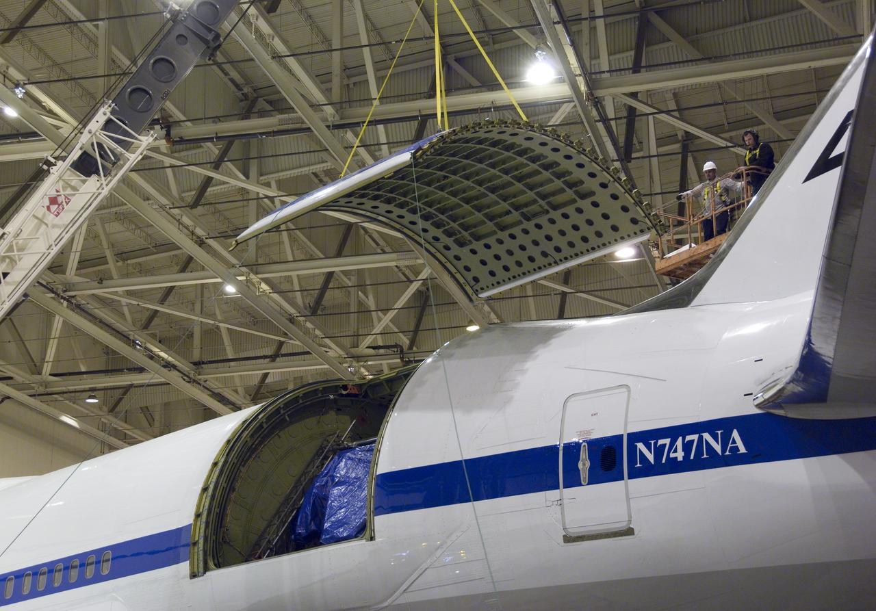 Technicians guide removal of the upper rigid door assembly that covers the telescope cavity on NASA's SOFIA 747SP in preparation for primary mirror removal.