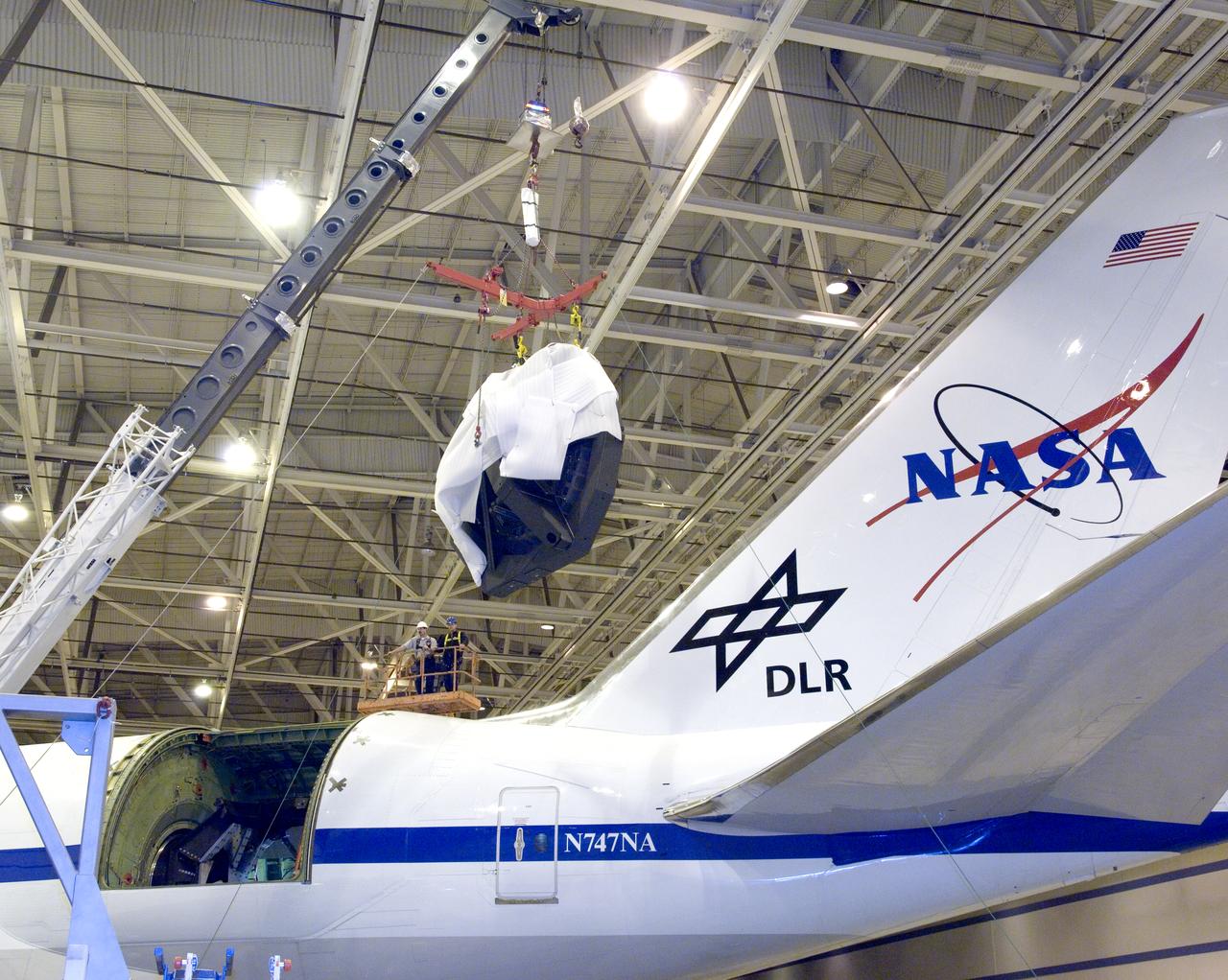 Technicians at the NASA Dryden Aircraft Operations Facility in Palmdale, Calif., removed the German-built primary mirror assembly from the Stratospheric Observatory for Infrared Astronomy, or SOFIA, April 18, 2008 in preparation for the final finish coating of the mirror. A precision crane lifted the more than two-ton mirror assembly from its cavity in the rear fuselage of the highly modified Boeing 747SP. The assembly was then secured in its transport dolly and moved to a clean room where it was prepared for shipment to NASA Ames Research Center at Moffett Field near Mountain View, Calif. where it would receive its aluminized finish coating before being re-installed in the SOFIA aircraft.