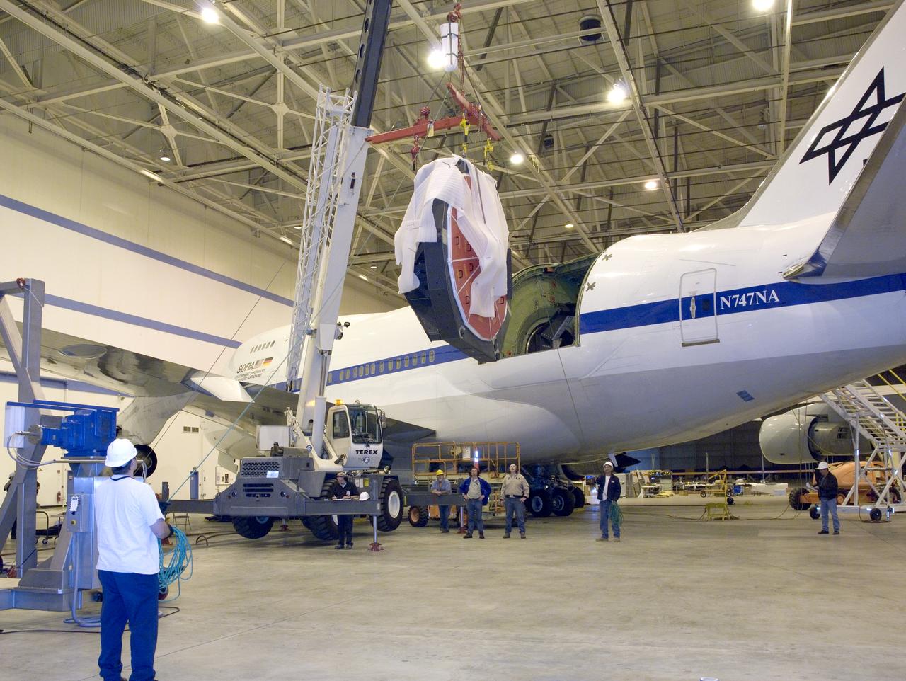 Technicians at the NASA Dryden Aircraft Operations Facility in Palmdale, Calif., removed the German-built primary mirror assembly from the Stratospheric Observatory for Infrared Astronomy, or SOFIA, April 18, 2008 in preparation for the final finish coating of the mirror. A precision crane lifted the more than two-ton mirror assembly from its cavity in the rear fuselage of the highly modified Boeing 747SP. The assembly was then secured in its transport dolly and moved to a clean room where it was prepared for shipment to NASA Ames Research Center at Moffett Field near Mountain View, Calif. where it would receive its aluminized finish coating before being re-installed in the SOFIA aircraft.