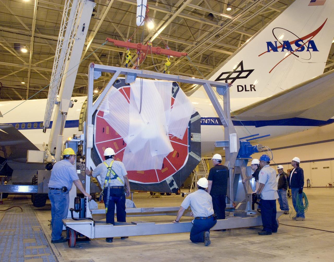 Technicians at the NASA Dryden Aircraft Operations Facility in Palmdale, Calif., removed the German-built primary mirror assembly from the Stratospheric Observatory for Infrared Astronomy, or SOFIA, April 18, 2008 in preparation for the final finish coating of the mirror. A precision crane lifted the more than two-ton mirror assembly from its cavity in the rear fuselage of the highly modified Boeing 747SP. The assembly was then secured in its transport dolly and moved to a clean room where it was prepared for shipment to NASA Ames Research Center at Moffett Field near Mountain View, Calif. where it would receive its aluminized finish coating before being re-installed in the SOFIA aircraft.