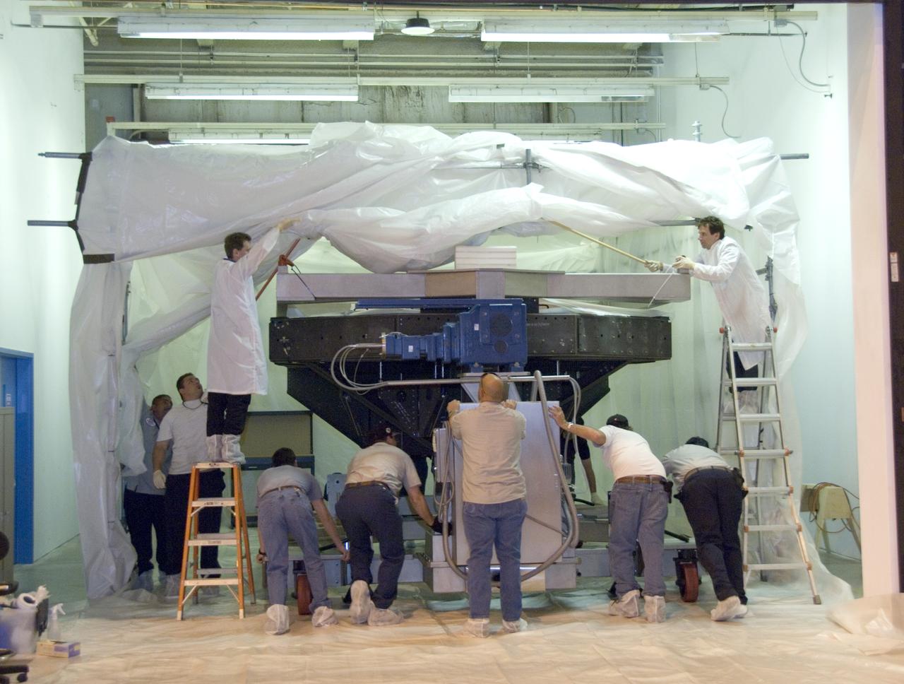 Technicians at the NASA Dryden Aircraft Operations Facility in Palmdale, Calif., removed the German-built primary mirror assembly from the Stratospheric Observatory for Infrared Astronomy, or SOFIA, April 18, 2008 in preparation for the final finish coating of the mirror. A precision crane lifted the more than two-ton mirror assembly from its cavity in the rear fuselage of the highly modified Boeing 747SP. The assembly was then secured in its transport dolly and moved to a clean room where it was prepared for shipment to NASA Ames Research Center at Moffett Field near Mountain View, Calif. where it would receive its aluminized finish coating before being re-installed in the SOFIA aircraft.