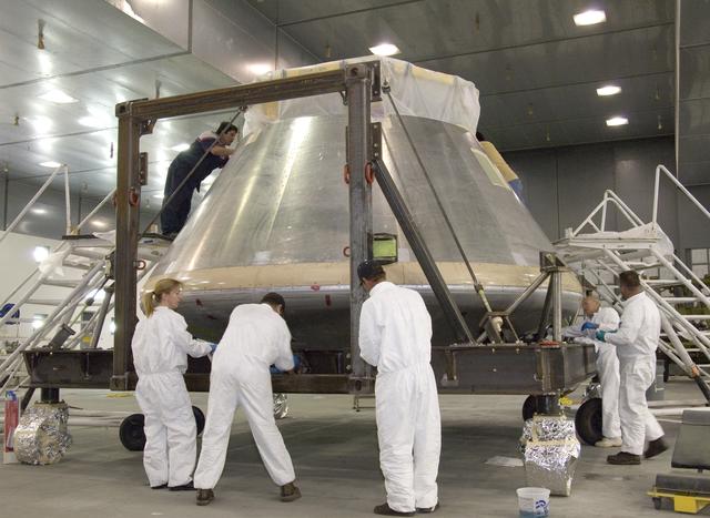 NASA image: NASA paint shop technicians prepare the Orion full-scale flight test crew module for painting in the Edwards Air Force Base paint hangar.