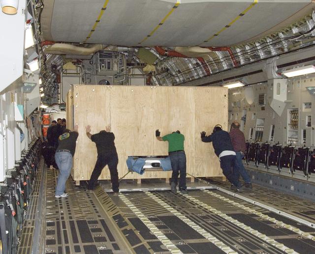 NASA image: Ground crewmen shove the more than two-ton SOFIA primary mirror assembly in its transport crate into a C-17's cavernous cargo bay for shipment to NASA Ames