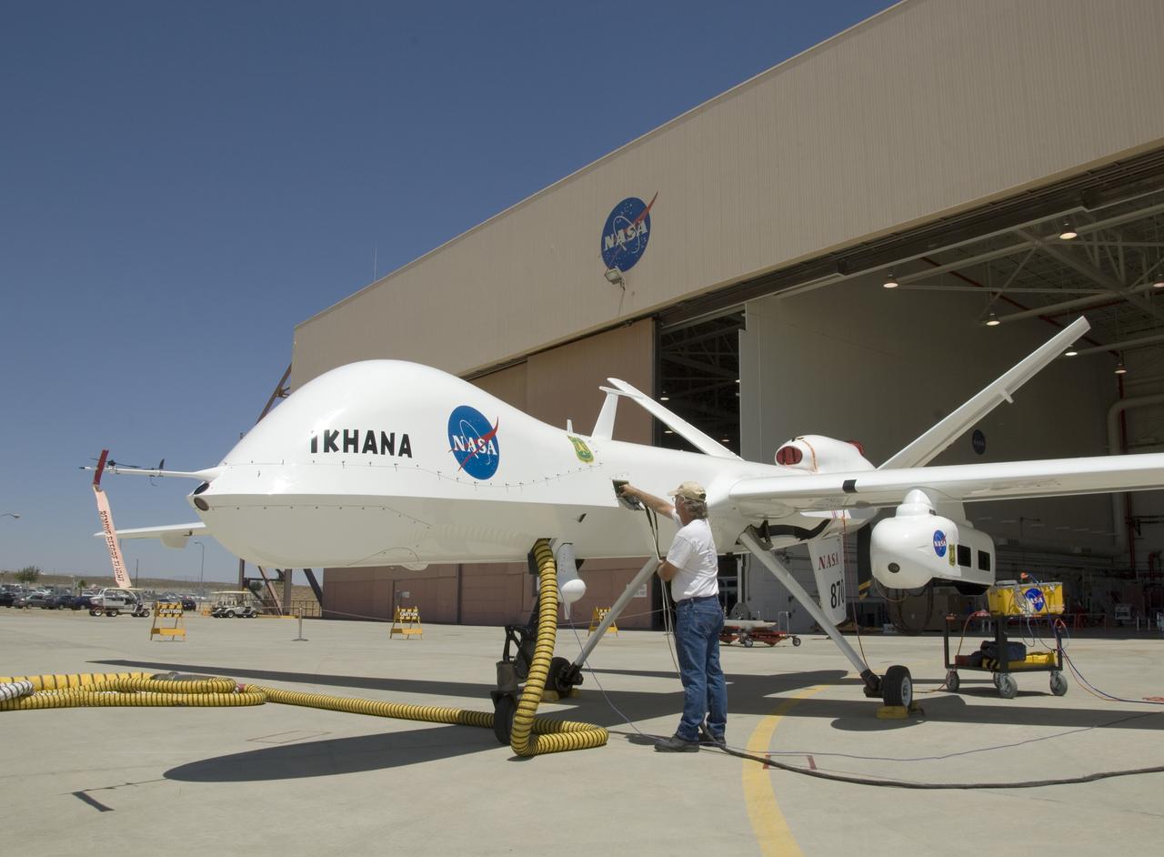 A ground crewman unplugs electrical connections during pre-flight checks of NASA's Ikhana research aircraft. Ikhana's payload pod is mounted on the left wing.