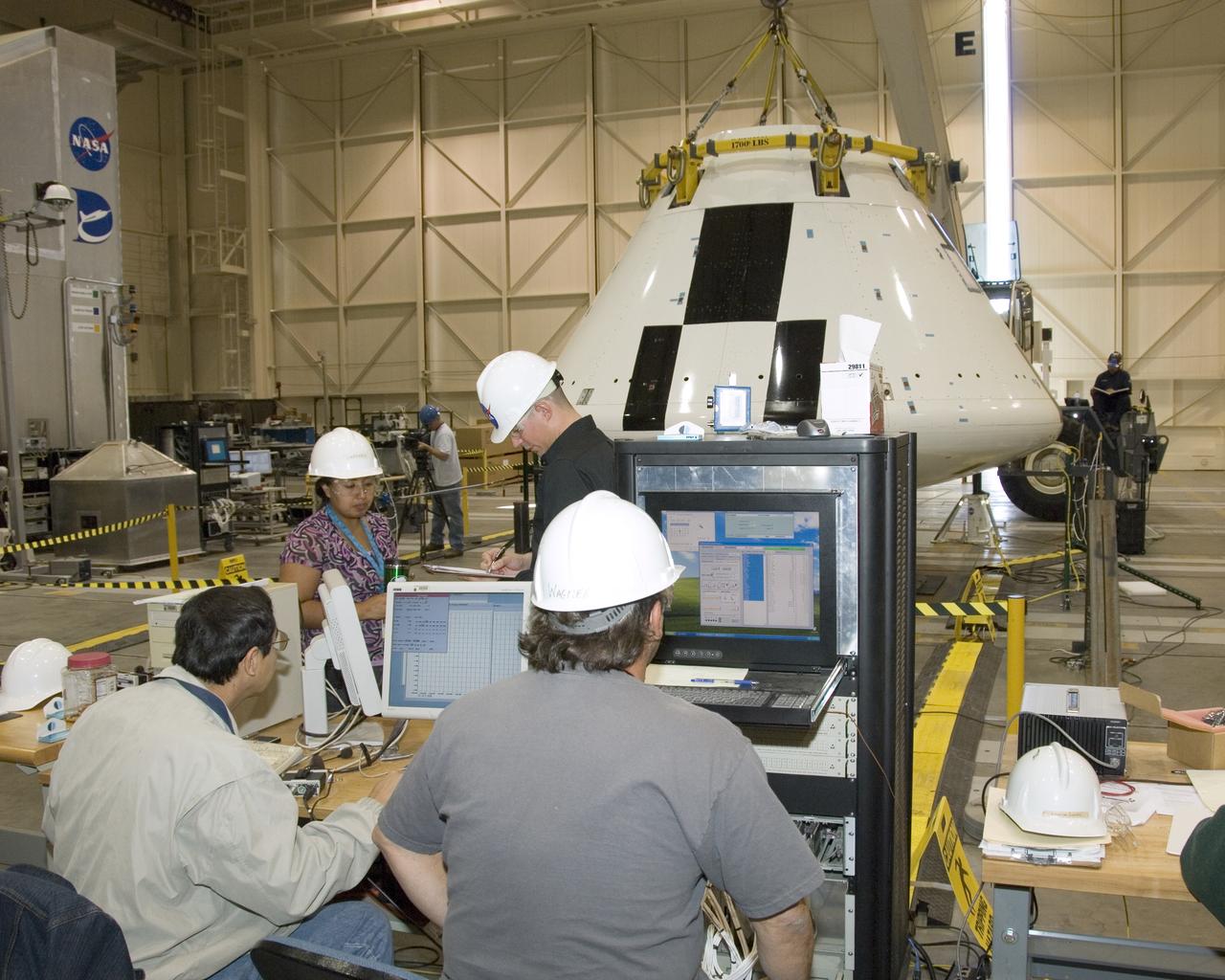 Engineers and technicians pore over data during moment-of-inertia testing on the Orion PA-1 Abort Flight Test module in the NASA Dryden Flight Loads Laboratory.