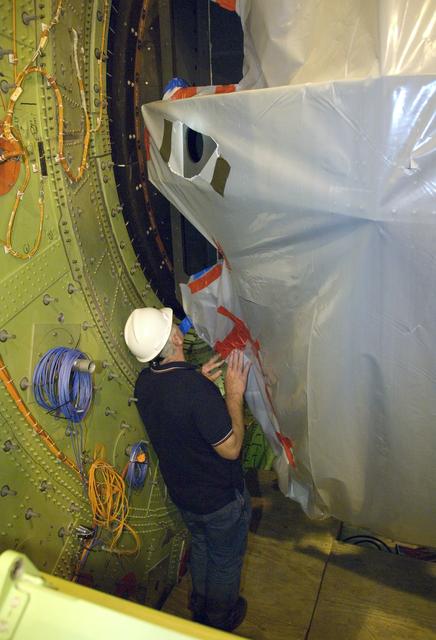 A technician guides SOFIA's primary mirror assembly into the aircraft's telescope cavity completing the mirror reinstallation following its initial coating