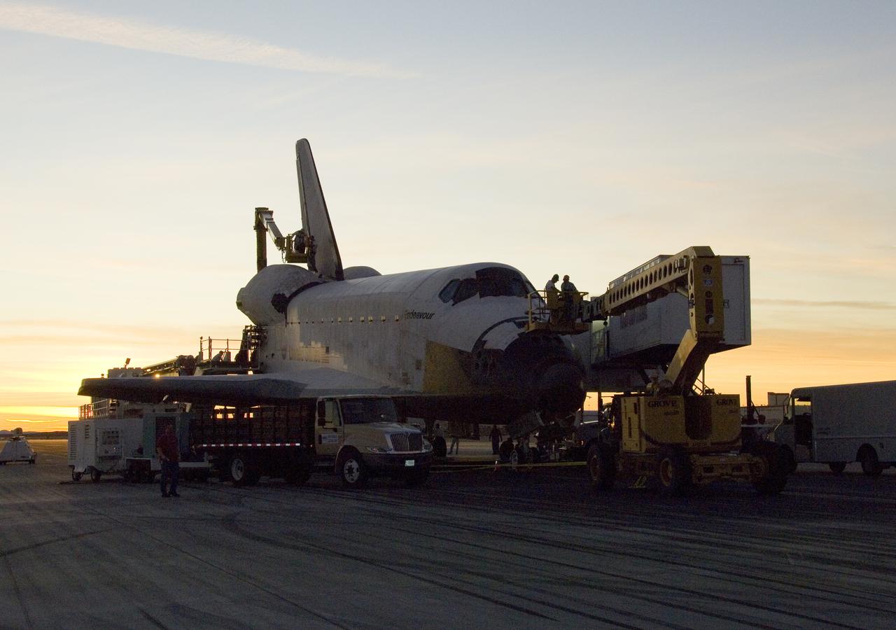 As the sun sets over the high desert, NASA technicians on mobile high-lifts prepare the shuttle Endeavour for towing off the Edwards Air Force Base runway.
