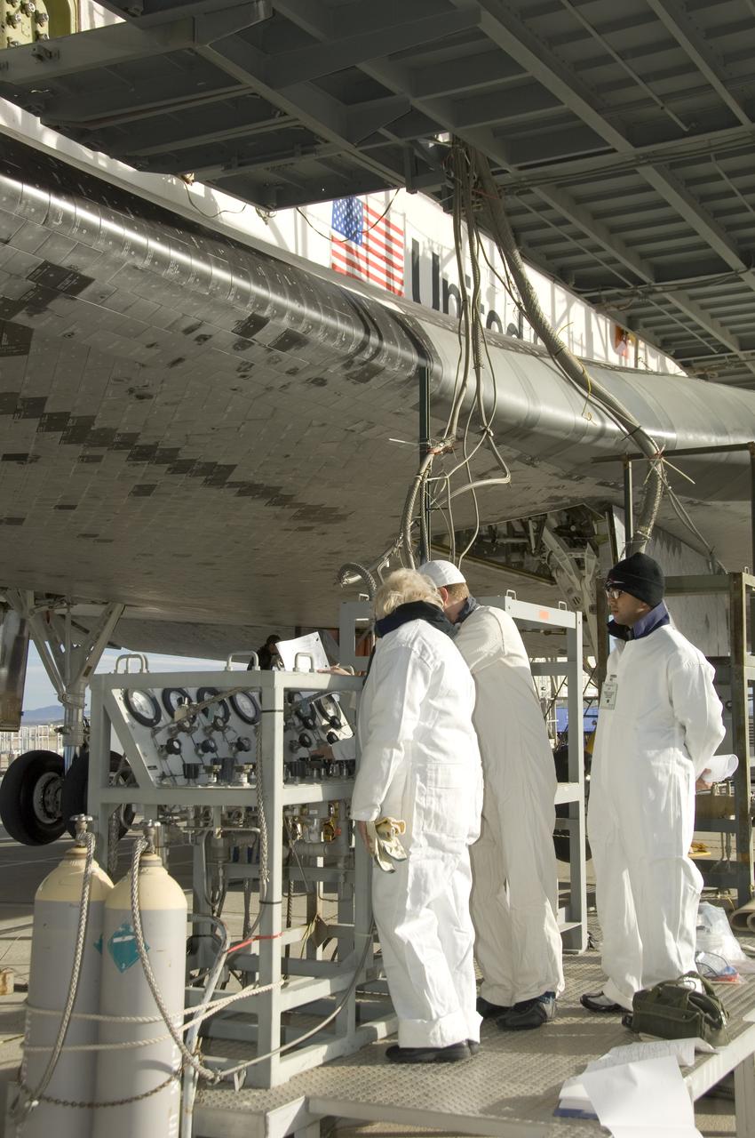 Technicians in protective coveralls check pressures of fluid systems during deservicing operations on Space Shuttle Endeavour after its landing at Edwards Air Force Base Nov. 30, 2008.